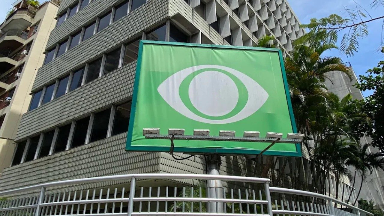 Prédio da sede da Band no Rio de Janeiro com logotipo verde da emissora em painel externo e árvores ao redor
