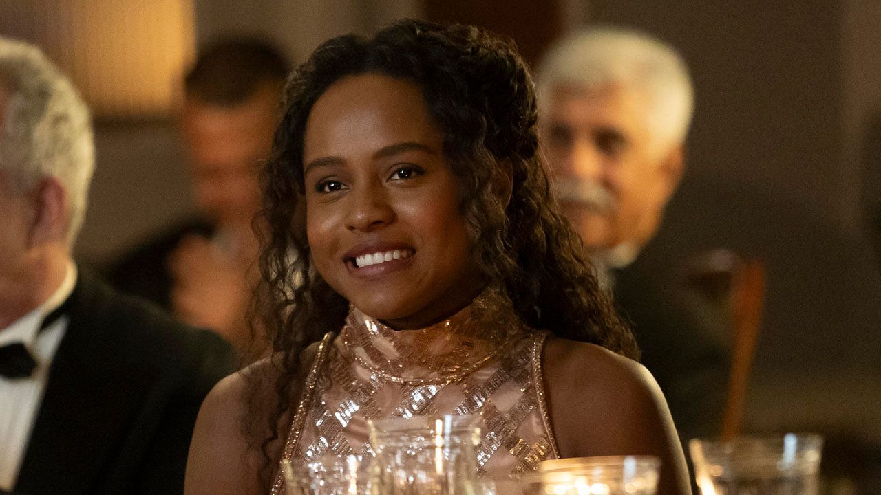 Duda Santos caracterizada como Beatriz sorrindo em cena de Garota do Momento durante evento elegante