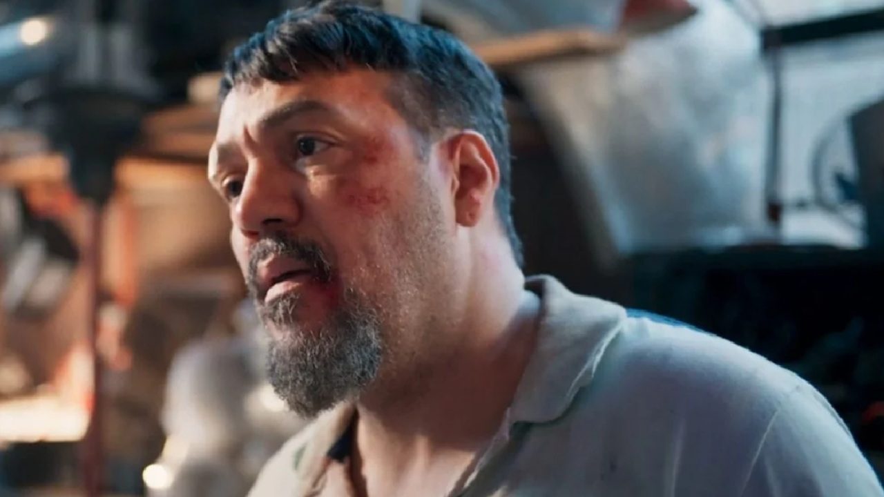 Belo com expressão abatida e marcas no rosto em ambiente industrial com iluminação suave