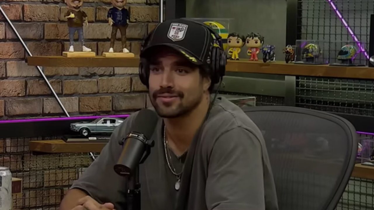 Homem de boné e fones de ouvido fala ao microfone durante gravação de podcast em estúdio decorado