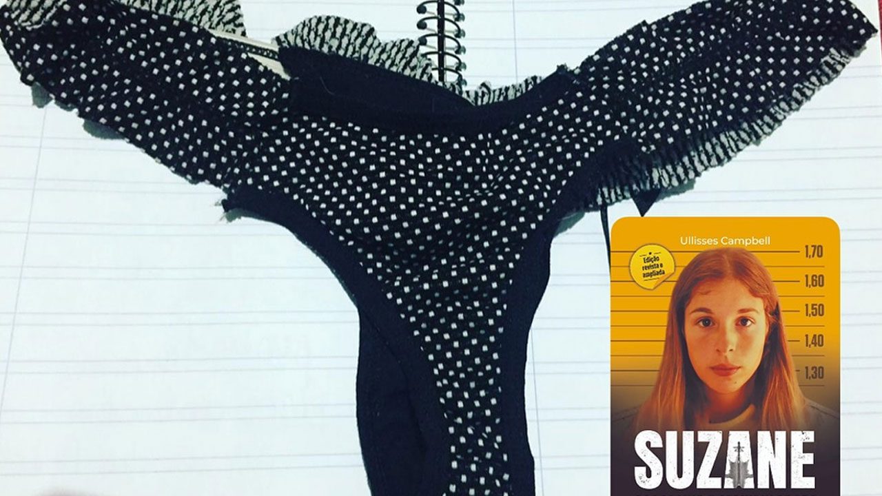 Calcinha preta de bolinhas brancas com babados sobre um caderno pautado ao lado do livro sobre Suzane von Richthofen