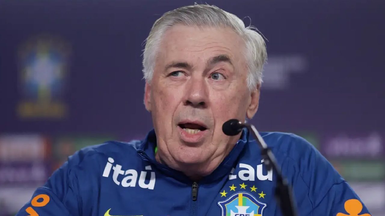 Homem com agasalho da Seleção Brasileira fala ao microfone durante coletiva de imprensa