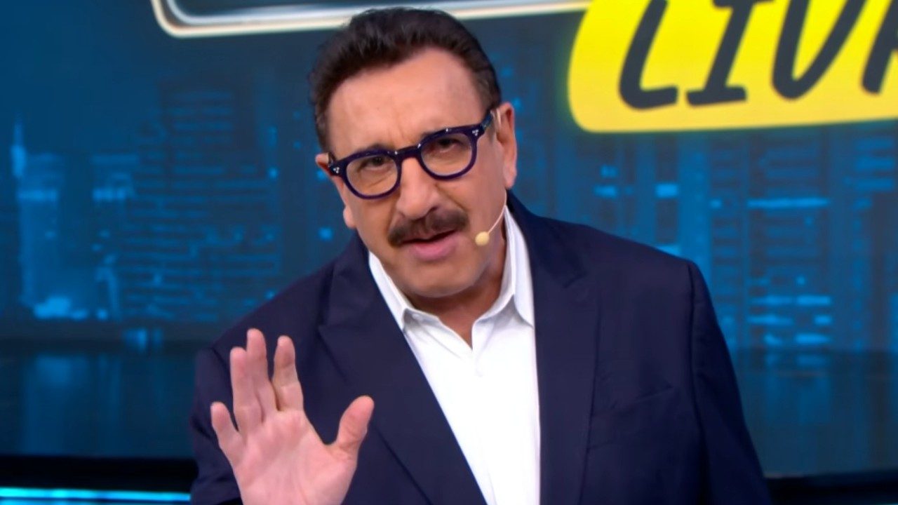 Carlos Massa Ratinho de terno azul e camisa branca faz gesto com a mão durante apresentação em estúdio de TV