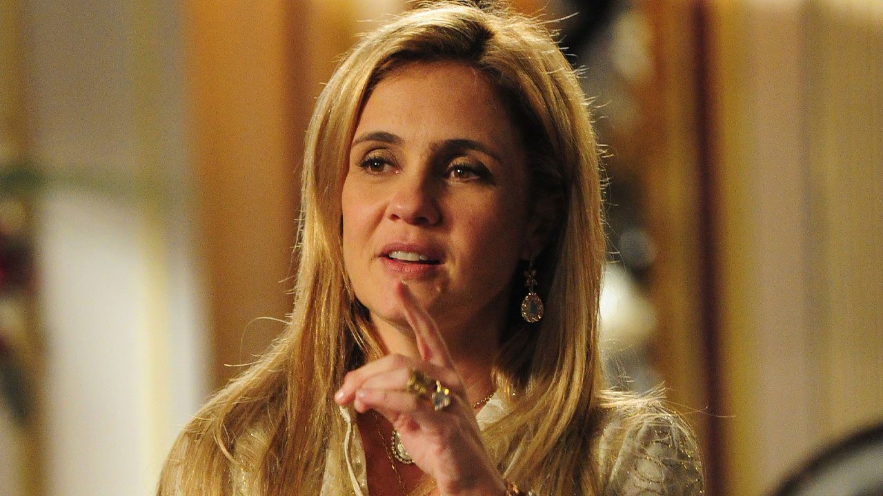 Adriana Esteves como Carminha com cabelo loiro, usando brincos e anéis grandes em cena da novela Avenida Brasil