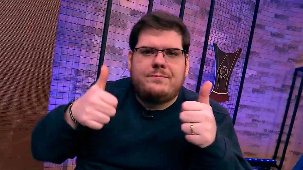 Casimiro Miguel no estúdio da CazéTV fazendo sinal de positivo com as duas mãos