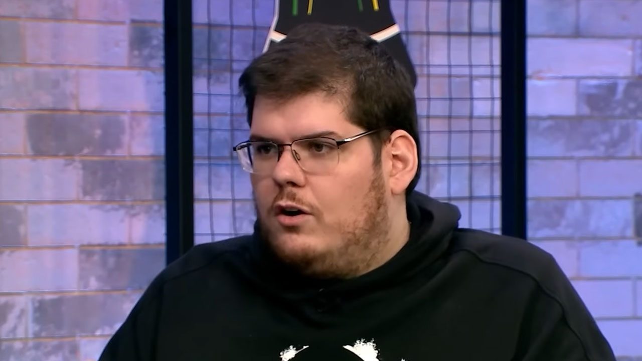 Casimiro Miguel durante participação em programa com cenário de tijolos aparentes e camiseta preta