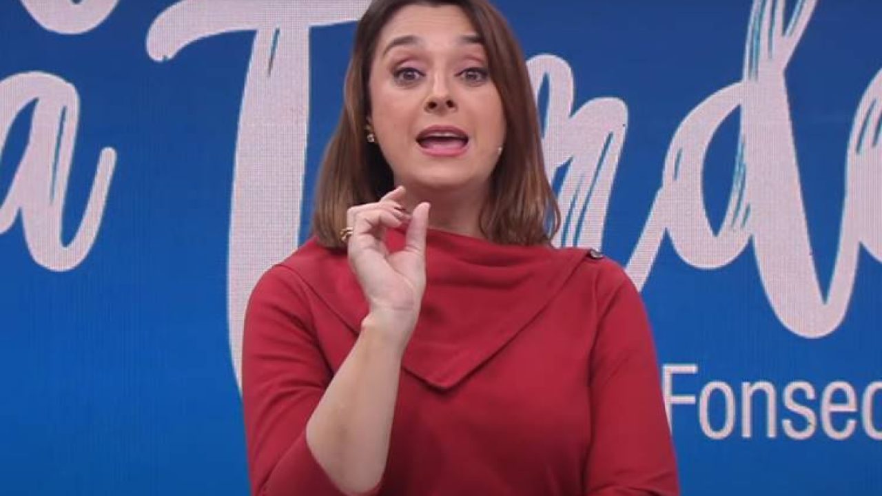 Catia Fonseca apresentando o Melhor da Tarde diante de telão com seu nome ao fundo