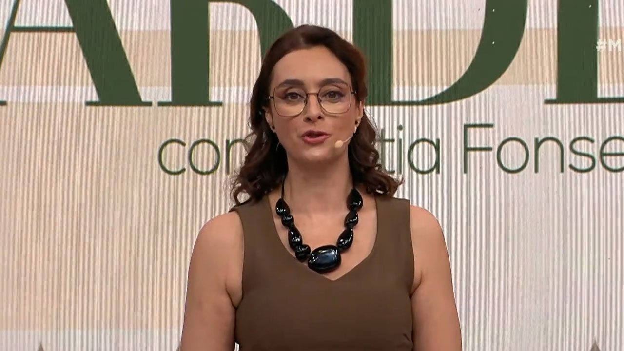 Catia Fonseca apresentando o Melhor da Tarde em frente ao telão com o nome do programa na Band