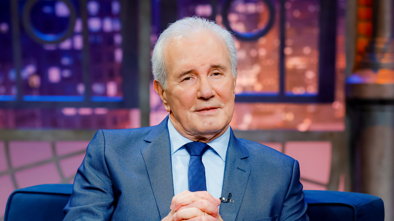 Celso Freitas sentado no sofá do The Noite do SBT durante entrevista no estúdio do programa