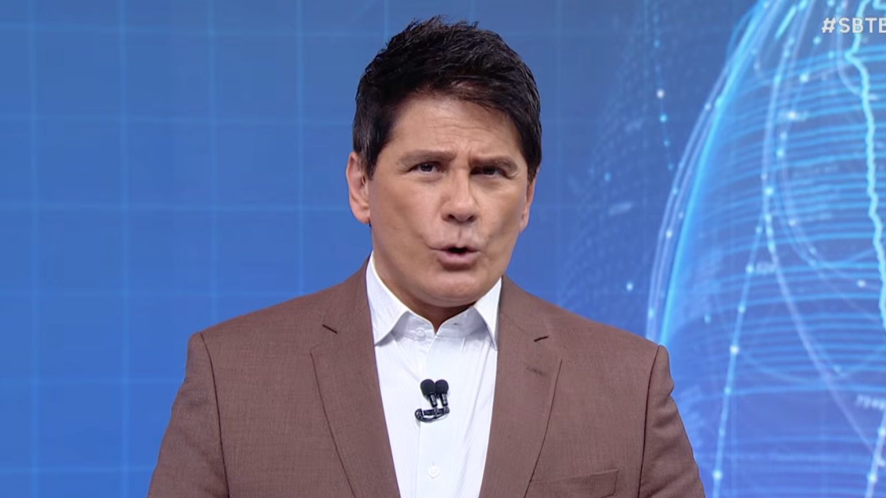 Cesar Filho, de blazer marrom e camisa branca, fala diante de painel azul com globo digital no SBT Brasil