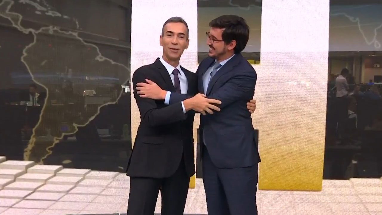 César Tralli e Nilson Klava se abraçam sorrindo no estúdio do Jornal Hoje da Globo