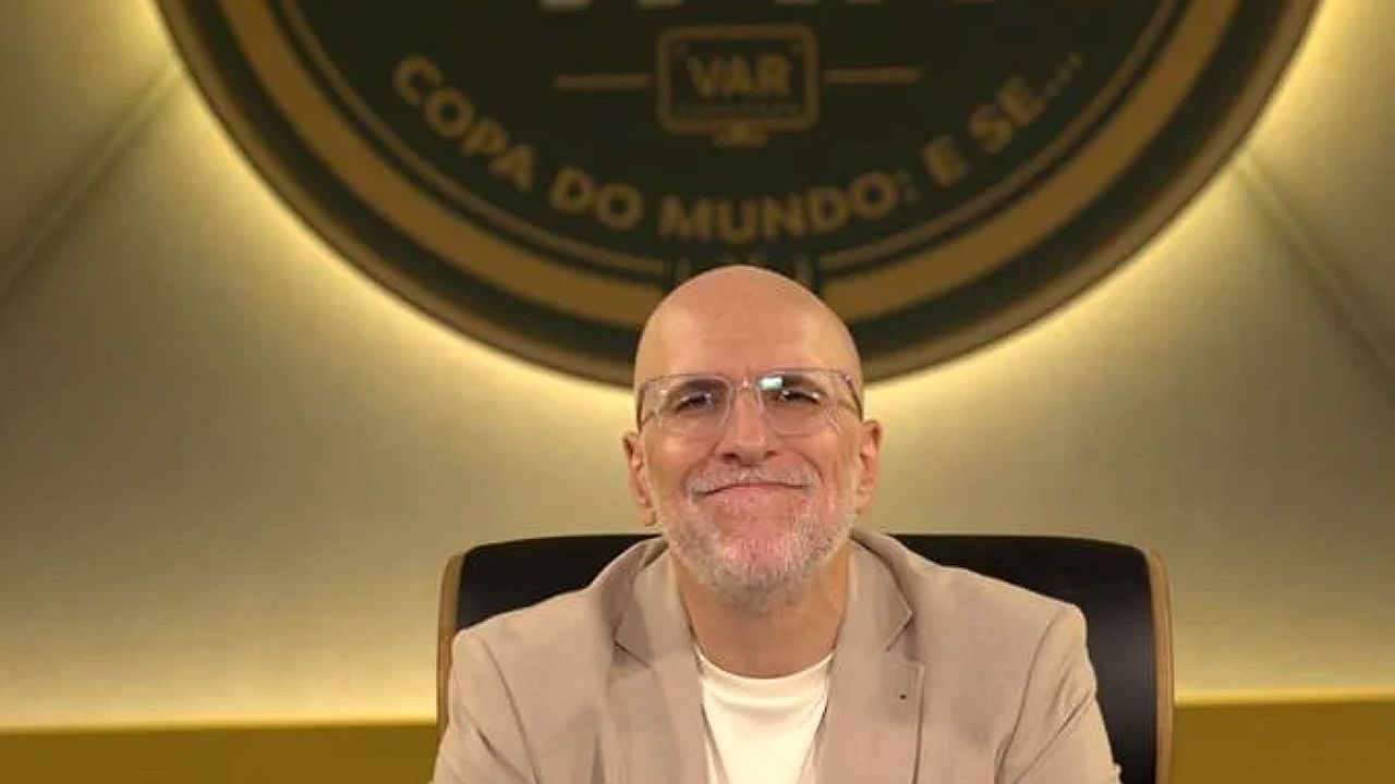 Antonio Tabet sentado em estúdio esportivo com logotipo ao fundo durante transmissão