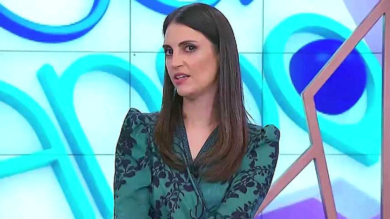 Chris Flores durante apresentação de programa de TV usando blusa verde estampada no estúdio da emissora