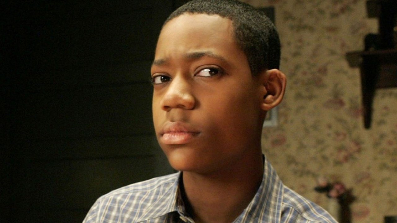 Ator Tyler James Williams interpretando Chris em Todo Mundo Odeia o Chris veste camisa xadrez azul e branca enquanto olha fixamente para o lado em cena