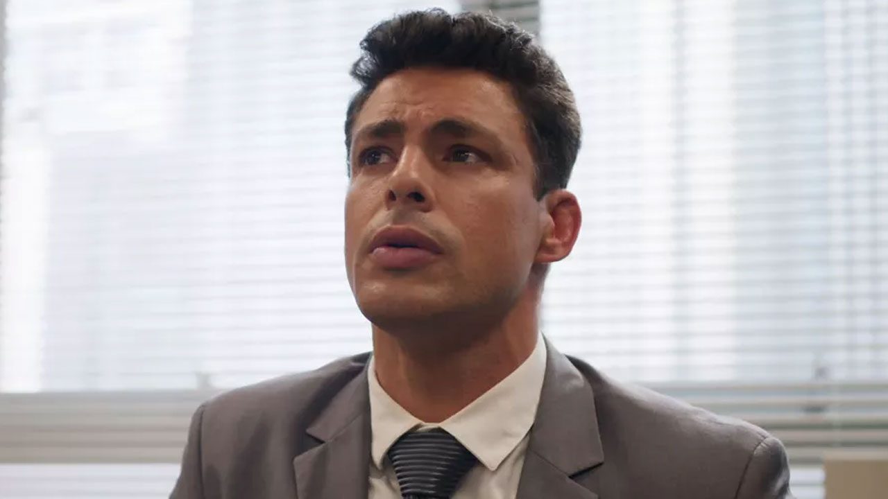 Cauã Reymond caracterizado como Christian/Renato usa terno cinza em cena da novela Um Lugar ao Sol