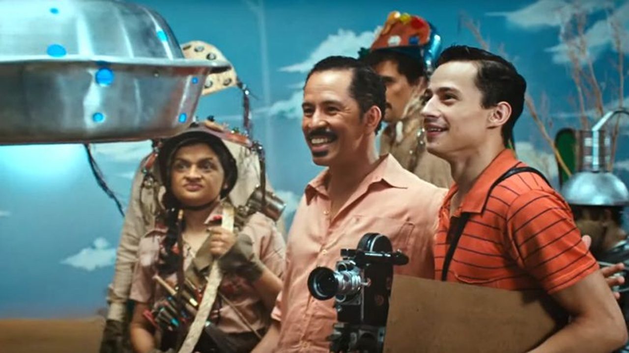 Homens observam nave cenográfica sorrindo em cena colorida de filme de comédia com figurinos criativos
