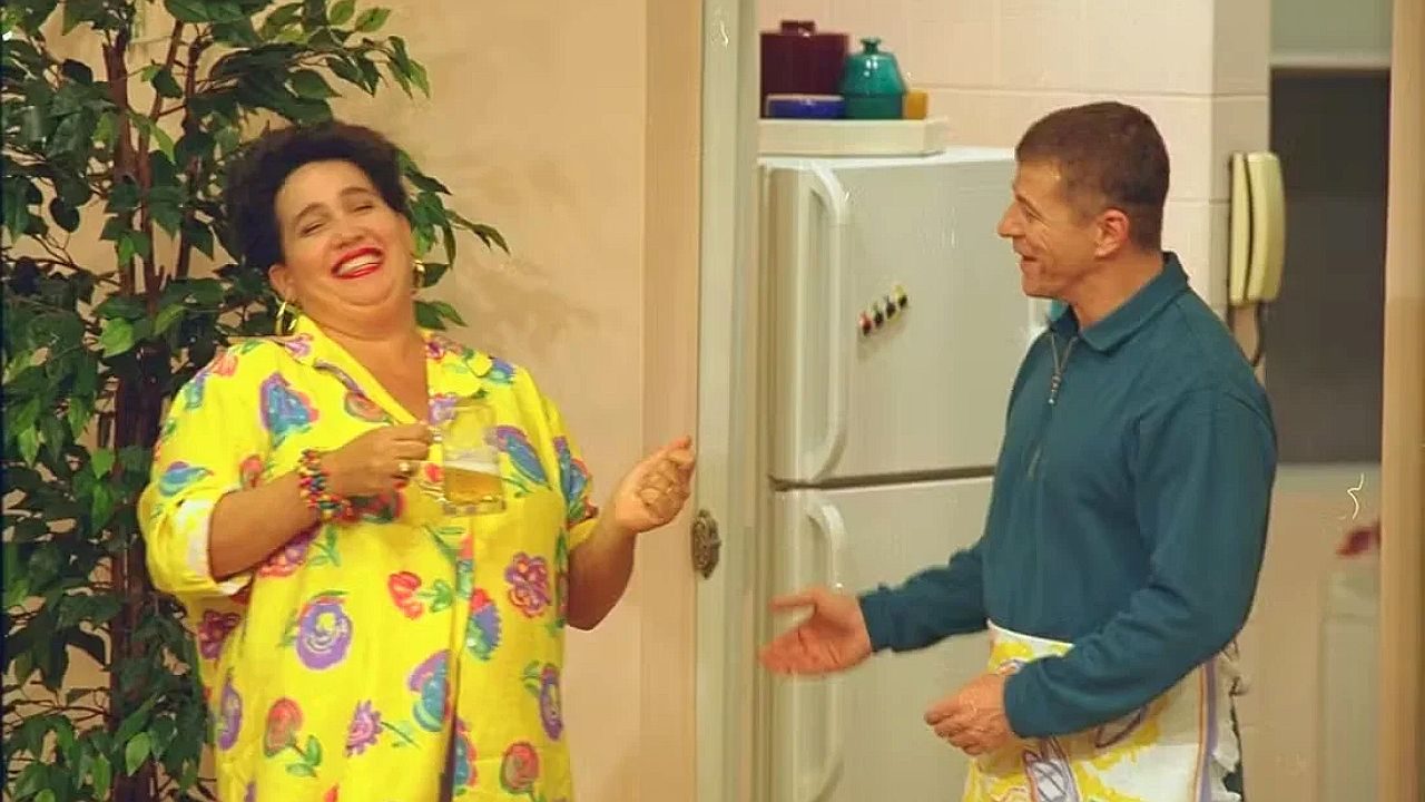 Cláudia Jimenez em cena cômica de Sai de Baixo na cozinha de apartamento familiar