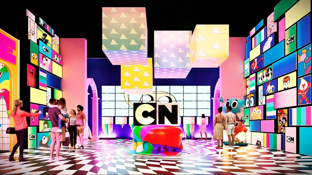 A CN Land será uma das atrações das férias escolares de julho no Shopping Center Norte, em São Paulo. A experiência interativa levará ao público cenários inspirados em animações do Cartoon Network, reunindo ambientes temáticos, recursos tecnológicos e percursos de aventura baseados em personagens conhecidos de diferentes gerações. Segundo a organização, a CN Land foi desenvolvida para ir além de uma exposição tradicional. A proposta combina cenografia, atividades interativas e experiências multissensoriais inspiradas em séries como Ben 10, Laboratório de Dexter, Hora da Aventura, O Incrível Mundo de Gumball e Apenas um Show. CN Land reúne atrações para todas as idades Danielle Paulino, executiva da 2a1, explicou que o objetivo é aproximar o público dos universos das animações. “Nosso objetivo com a CN Land é extrapolar os limites da tela e permitir que o público, de diferentes gerações, sinta que realmente faz parte desses universos”, afirmou. Ela acrescentou que a experiência foi planejada para atender tanto crianças quanto adultos que acompanharam os desenhos ao longo dos anos. “Unimos a nostalgia dos personagens clássicos com o que há de mais moderno em tecnologia interativa e cenografia ponta a ponta, garantindo uma experiência memorável”, declarou. Exposição terá circuitos e desafios A programação contará com atrações inspiradas em diferentes produções do Cartoon Network. Em Ben 10, os visitantes encontrarão uma arena com plataforma giratória em 360 graus e jogos temáticos do Omnitrix. Hora da Aventura oferecerá desafios de arremesso e sistema de pontuação, enquanto As Meninas Superpoderosas terá estruturas suspensas que simulam voos sobre Townsville. A experiência ainda contará com um espaço dedicado a O Incrível Mundo de Gumball, equipado com tobogã e piscina de bolinhas, além de um circuito de aventura inspirado em Apenas um Show. Também fazem parte da exposição ambientes baseados em Urso sem Curso, Coragem, o Cão Covarde e Steven Universe, com atividades voltadas ao equilíbrio, desafios interativos, experiências sensoriais e espaços preparados para fotos e vídeos.