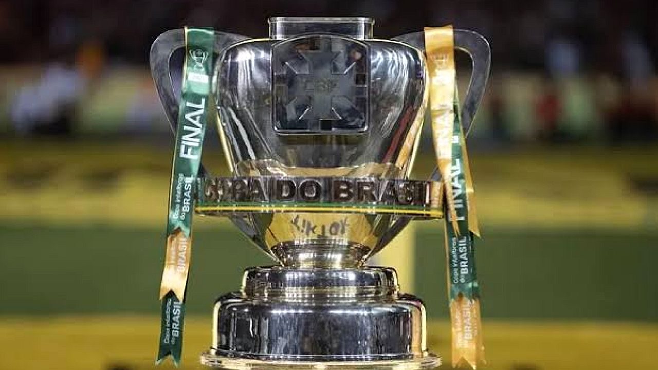 Troféu da Copa do Brasil em destaque no gramado com fitas da competição presas às alças