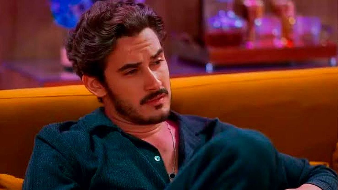 Filipe Bragança sentado em sofá com expressão séria em cena da novela Coração Acelerado
