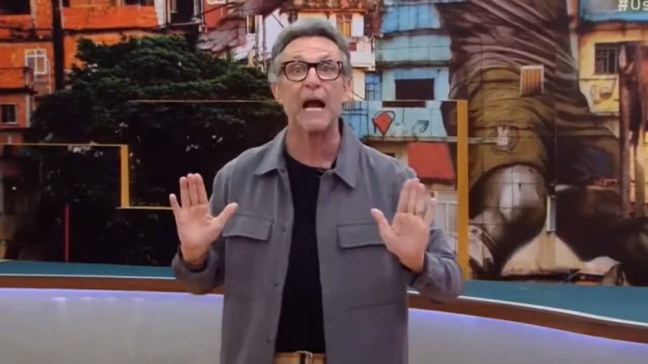 Craque Neto gesticula com as mãos erguidas enquanto apresenta o programa Os Donos da Bola na Band