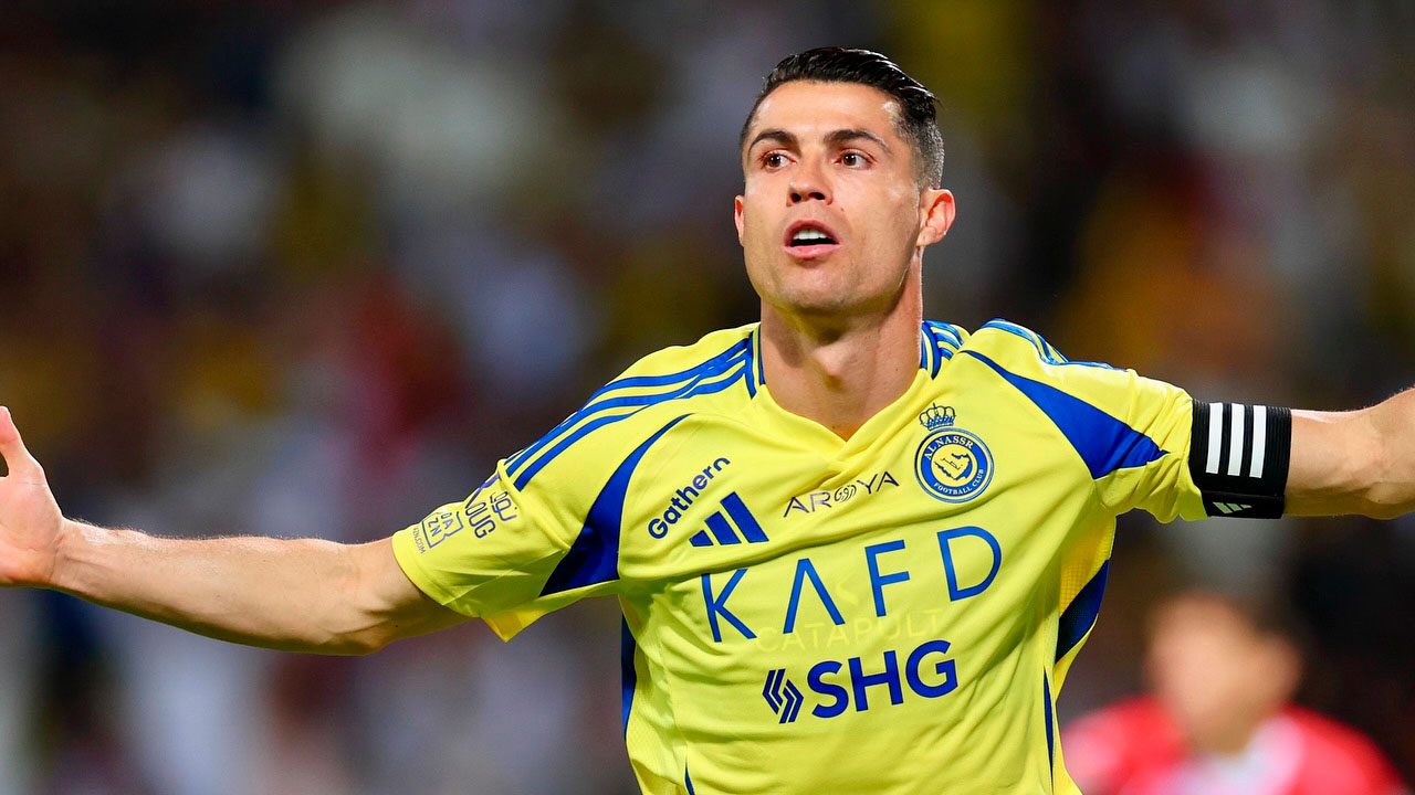 Cristiano Ronaldo comemorando gol com os braços abertos usando uniforme amarelo do Al-Nassr durante partida na Arábia Saudita