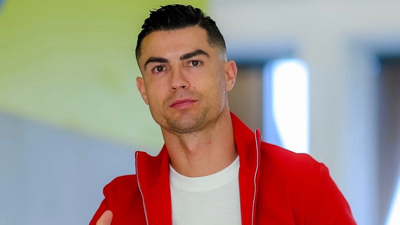 Cristiano Ronaldo usando jaqueta vermelha e camiseta branca em corredor iluminado durante aparição pública