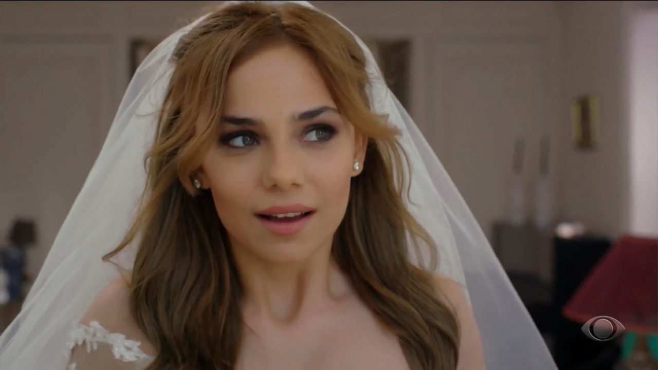 Em Cruel Istambul, personagem jovem vestida de noiva, com véu e vestido branco, olha surpresa para o lado em um ambiente interno elegante; no canto da tela aparece o logotipo da Band.