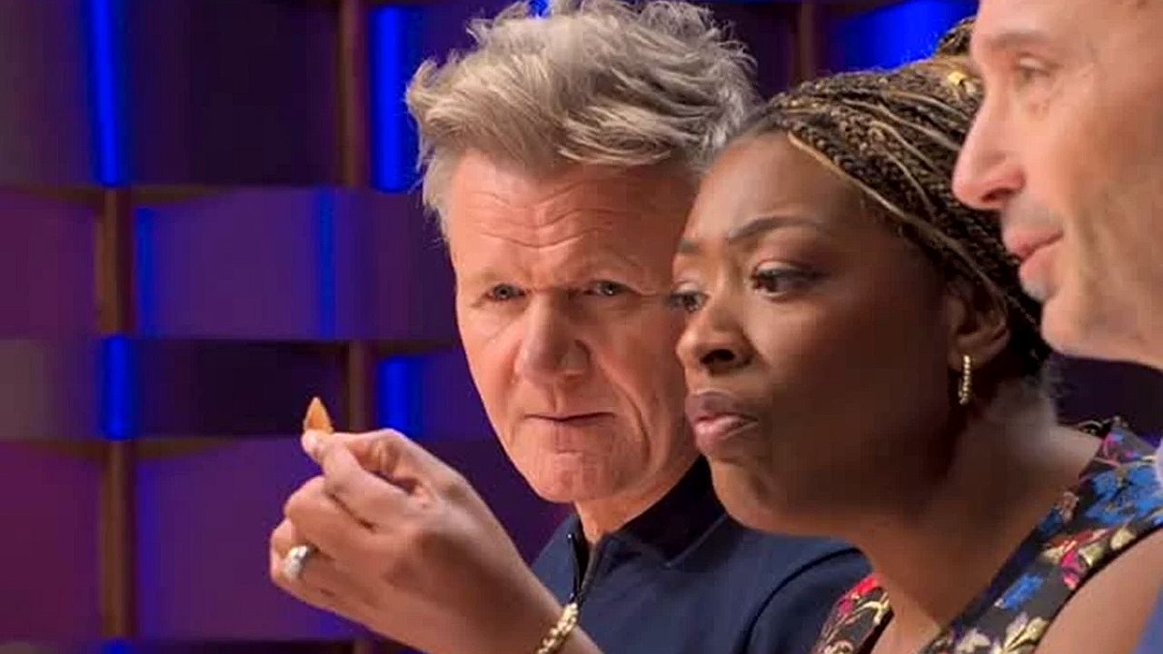 Gordon Ramsay observa participante durante prova culinária do MasterChef ao lado de jurados no estúdio