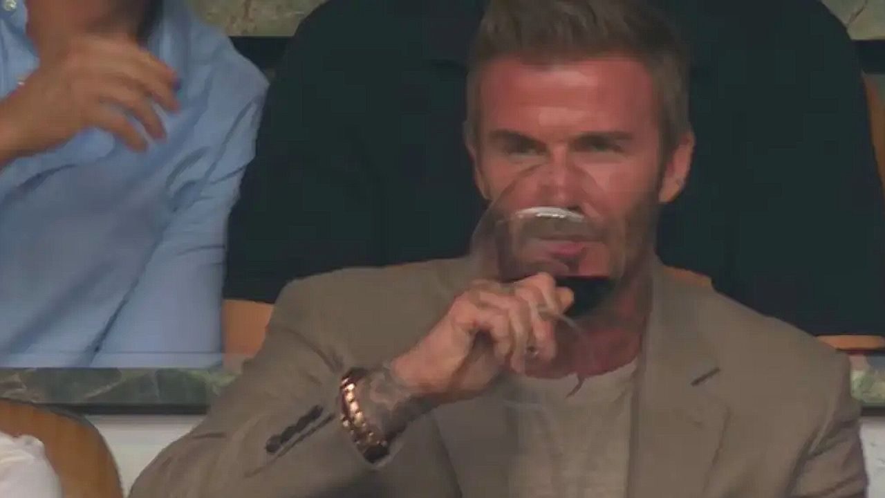 David Beckham assiste a partida de futebol enquanto segura taça de vinho na arquibancada do torneio
