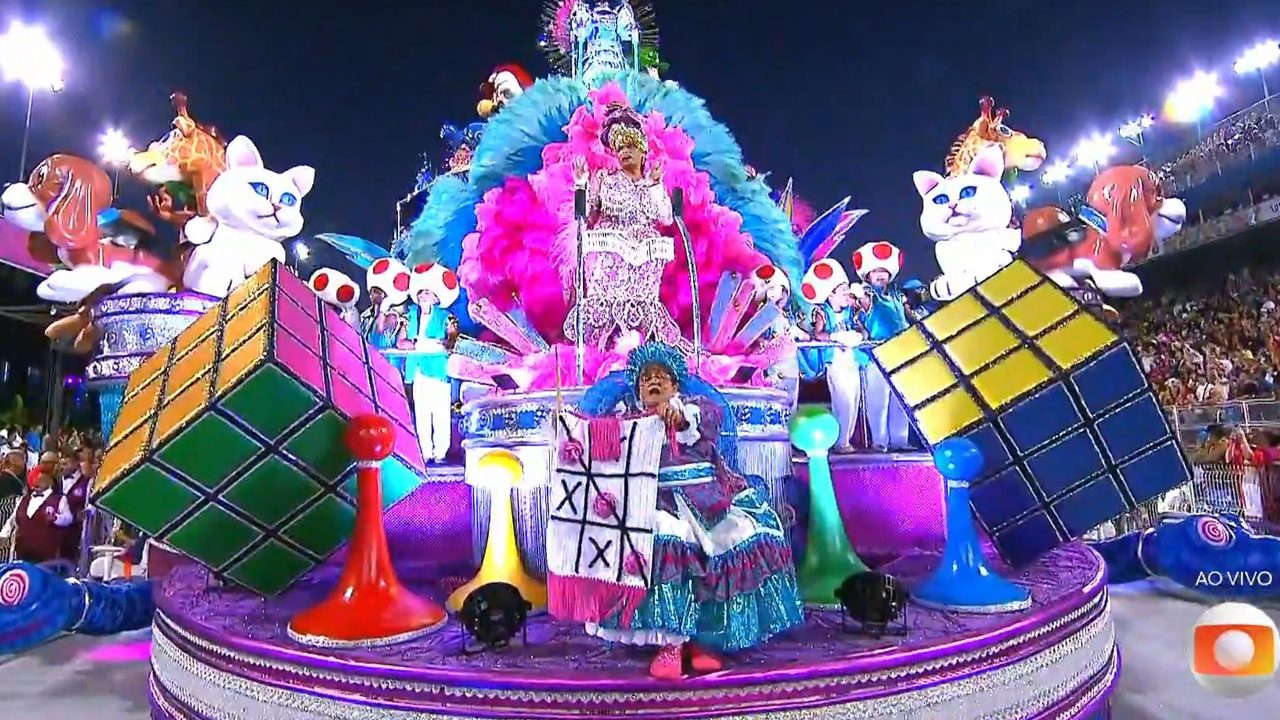 Carro alegórico da Rosas de Ouro com tema infantil e fantasias coloridas durante desfile transmitido pela Globo ao vivo