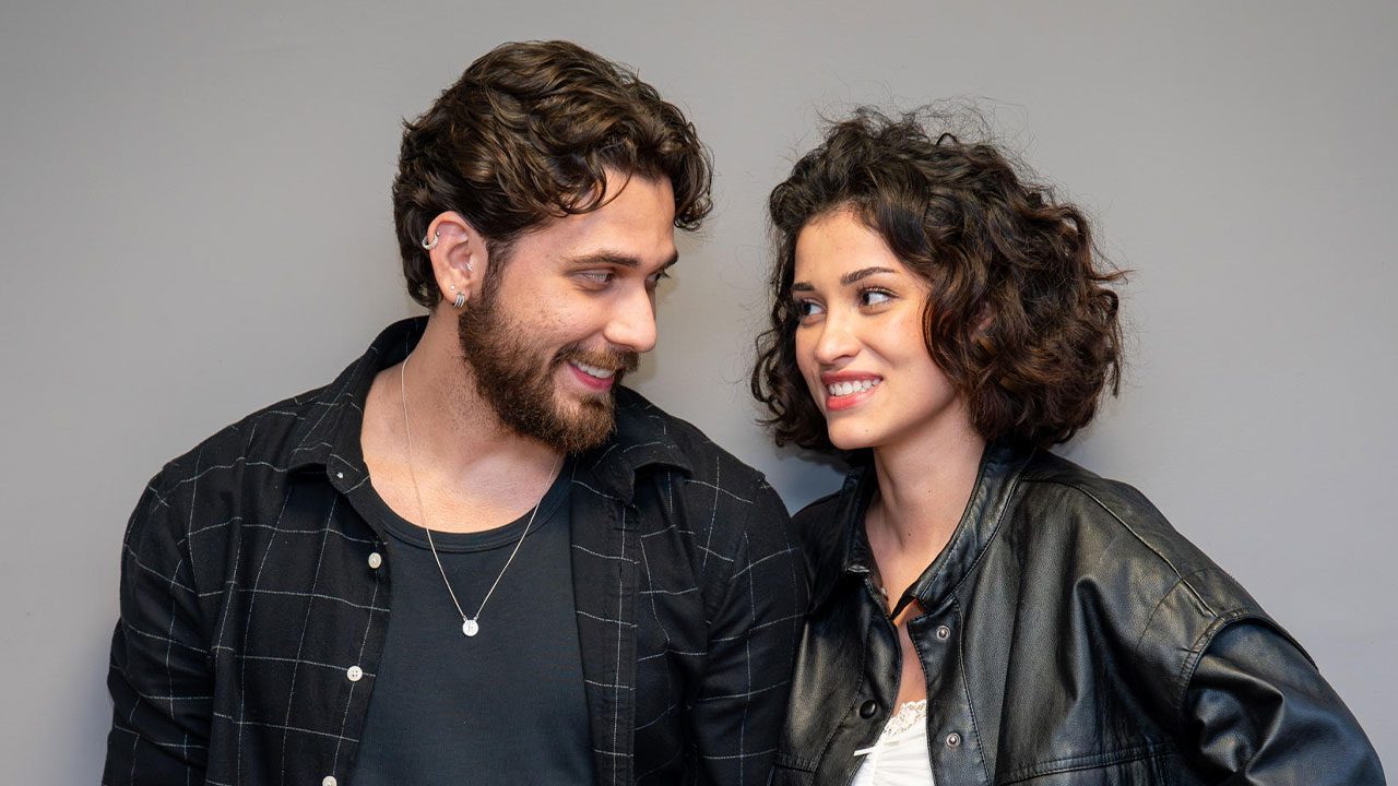 Gustavo Mioto como Diego e Maya Aniceto como Cindy sorrindo e se olhando em cena da novela Cinderela e o Pobre Milionário