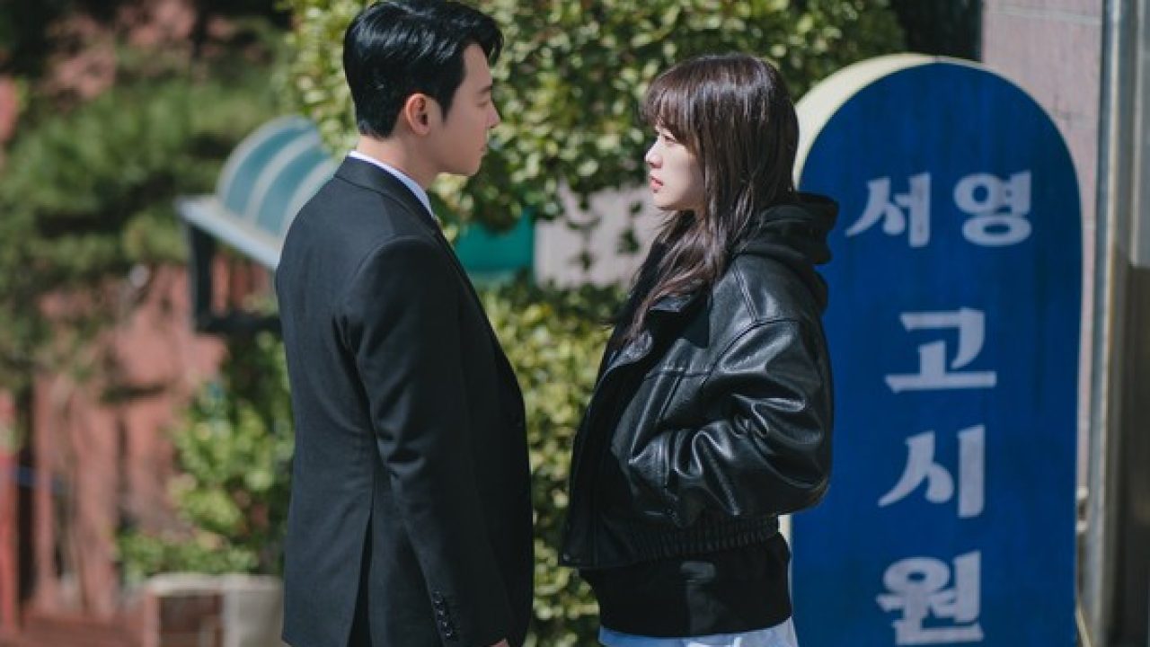 Personagens de Doce Engano se encaram em cena externa diante de uma pensão na Coreia do Sul