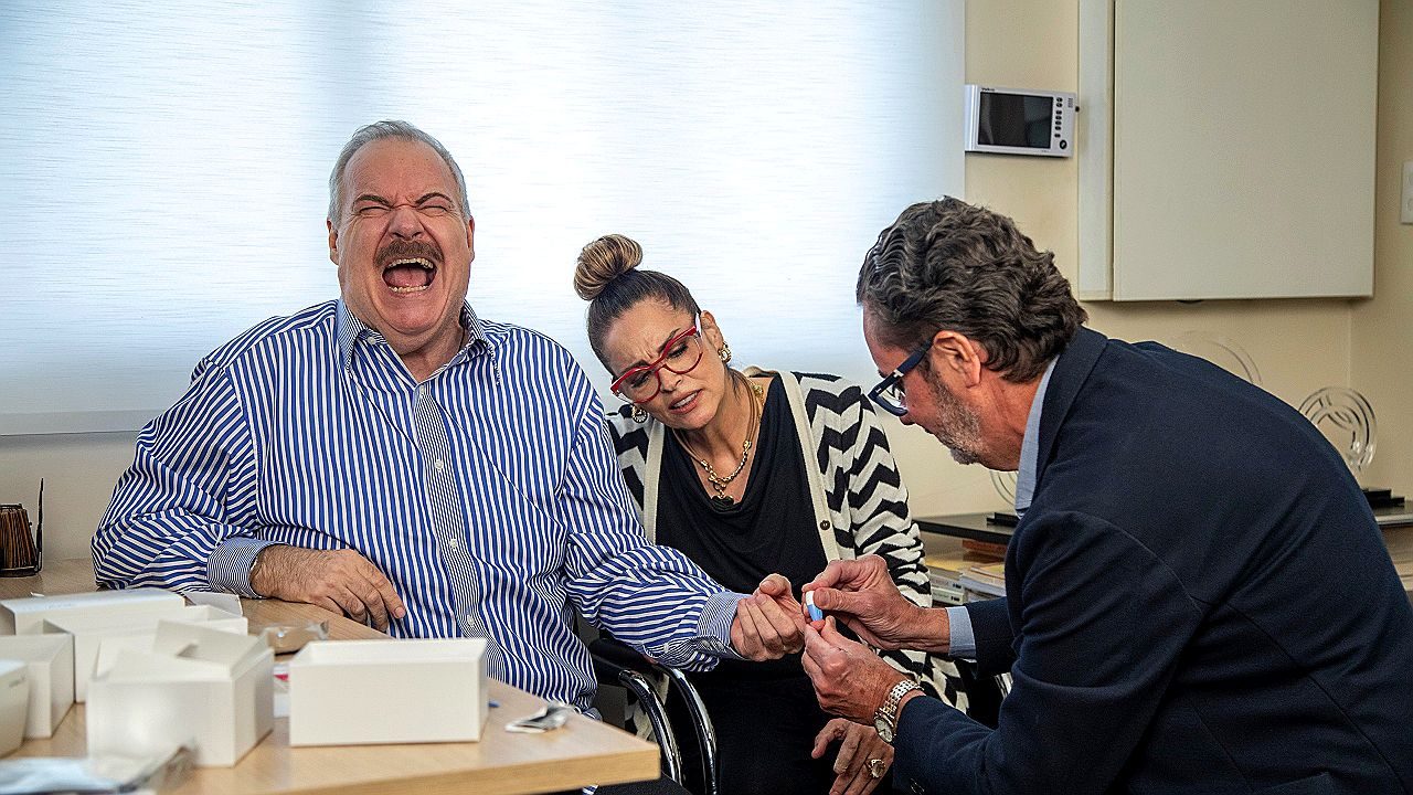 Gilberto Barros faz exame de glicemia com ajuda de médico enquanto Suzy Rêgo acompanha a consulta no Domingo Espetacular