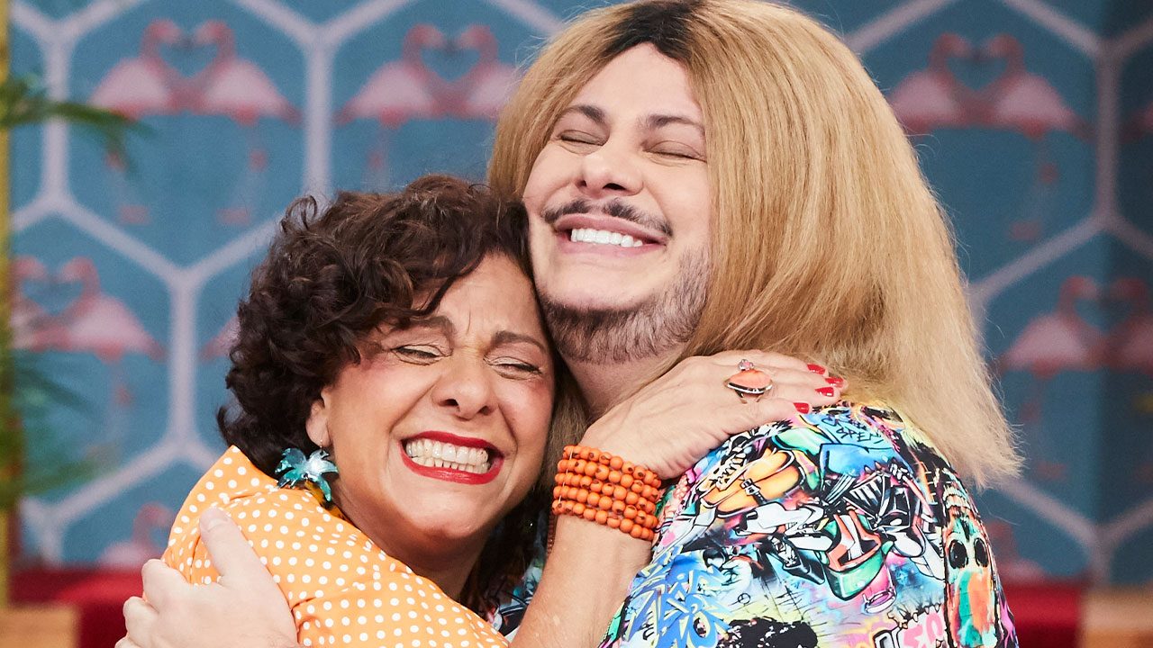 Catarina Abdalla como Dona Jô e Marcus Majella como Ferdinando se abraçando e sorrindo em cena de Vai que Cola