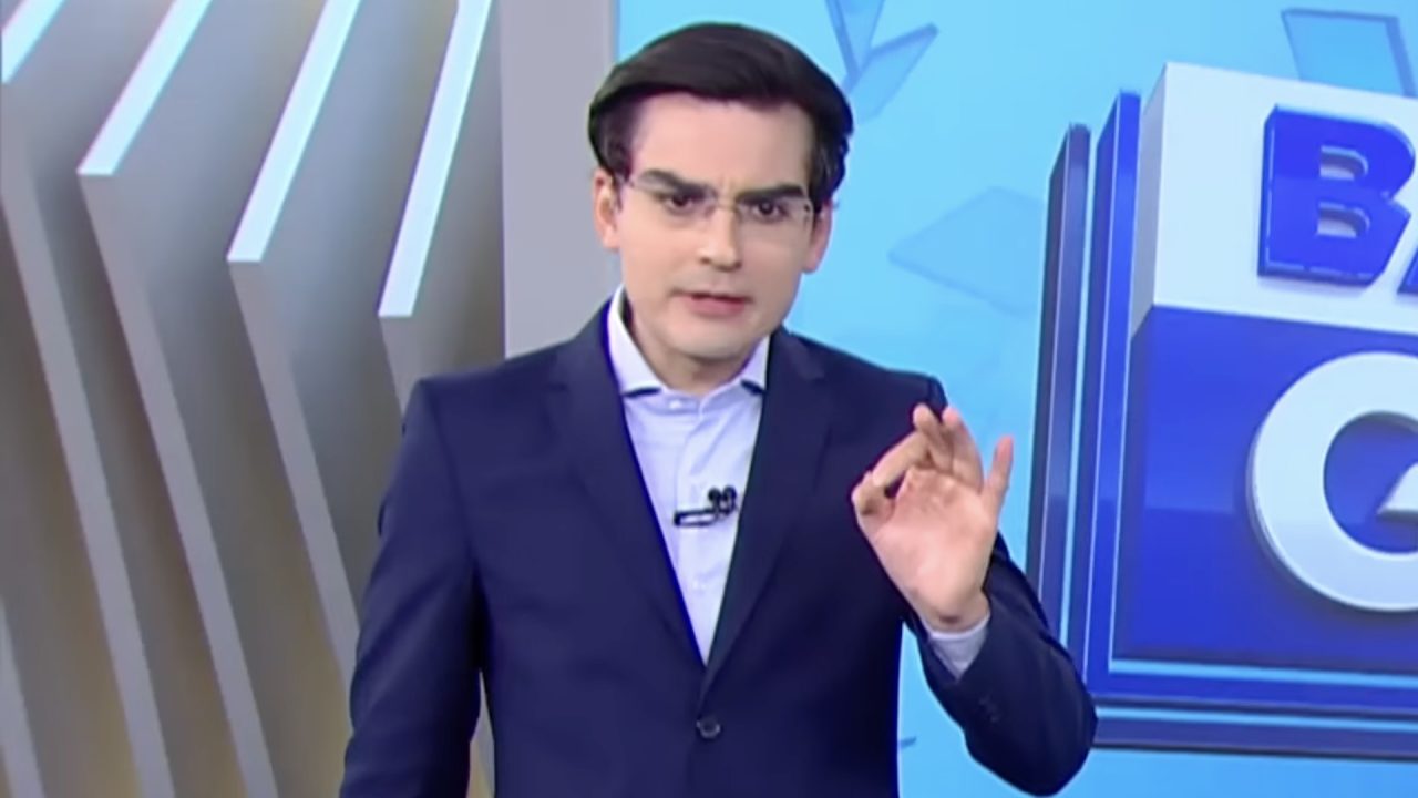 Dudu Camargo, de terno azul, faz gesto com a mão durante o Balanço Geral Manhã em estúdio da Record