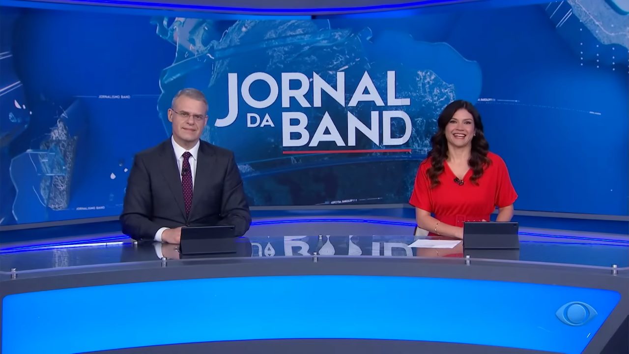 Foto de Eduardo Oinegue e Thais Dias na bancada do Jornal da Band