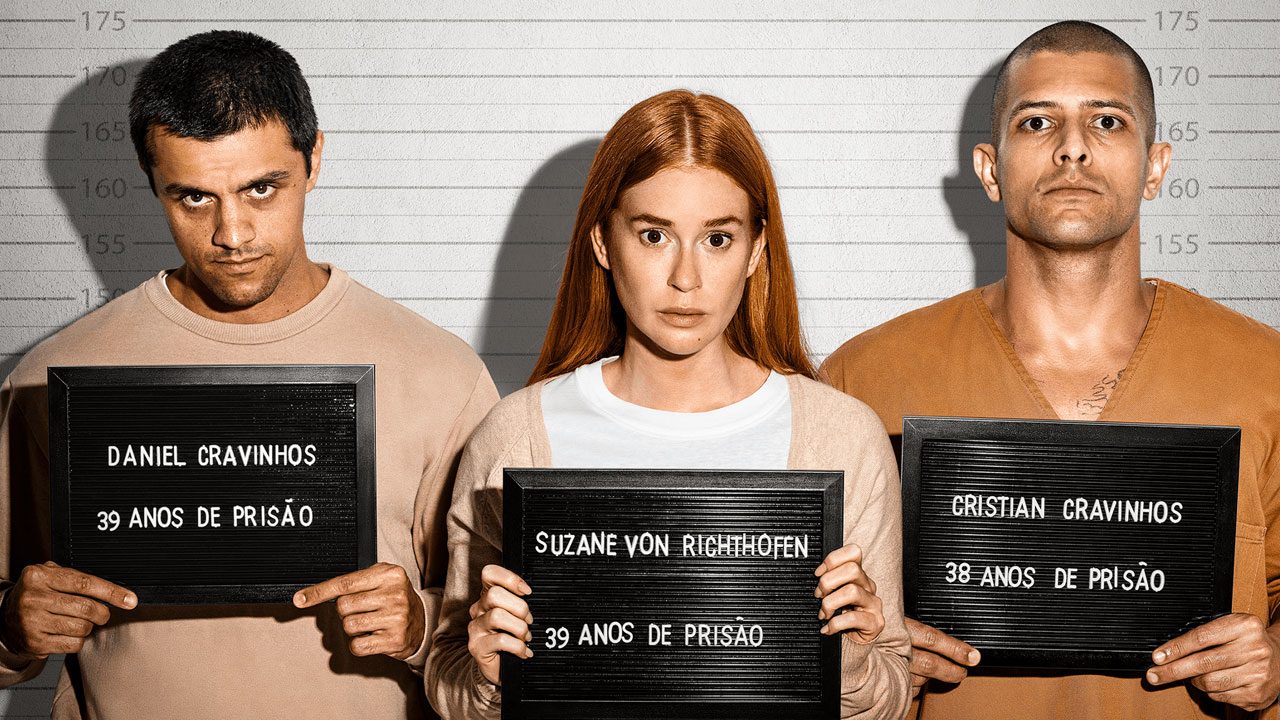 Felipe Simas, Marina Ruy Barbosa e Kelner Macêdo em mugshot para a série Tremembé, segurando placas com os nomes dos criminosos