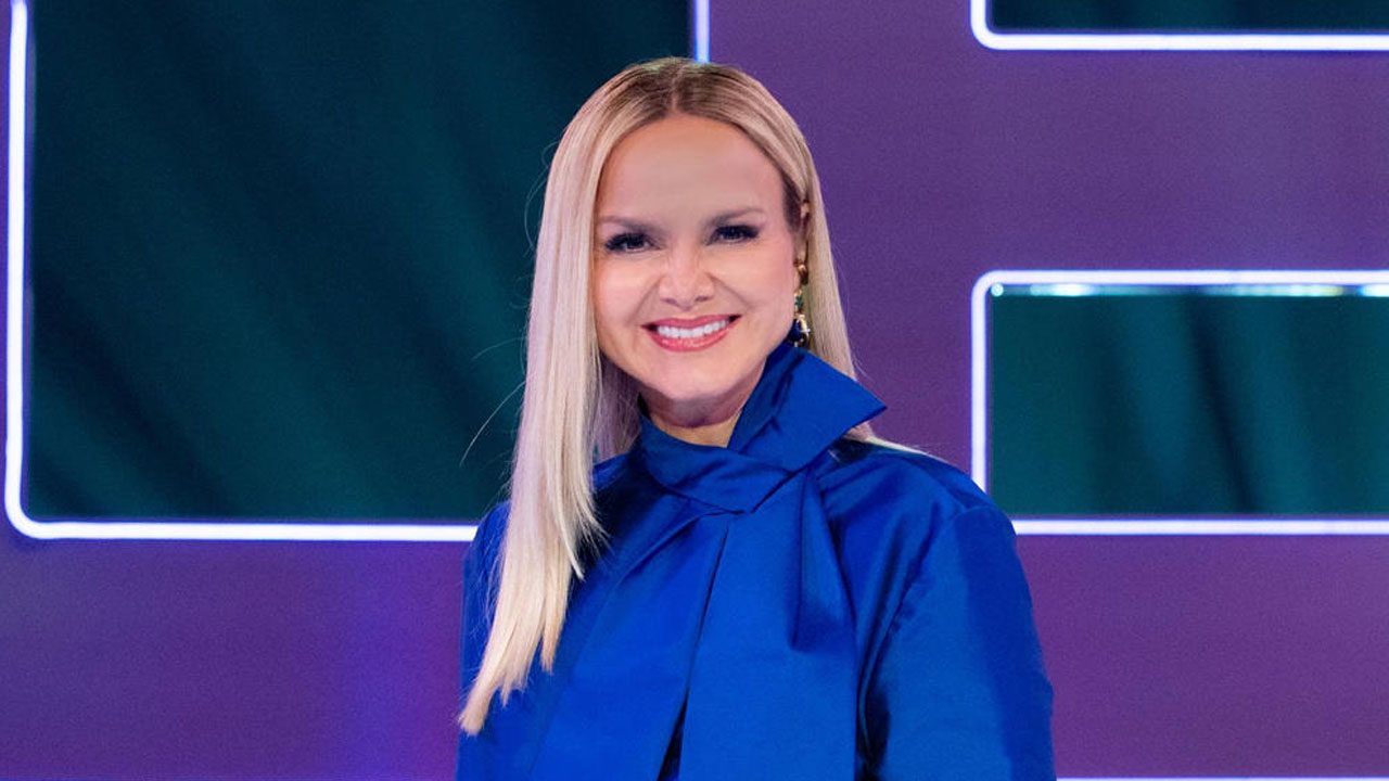 Eliana Michaelichen sorrindo com figurino azul em cenário iluminado