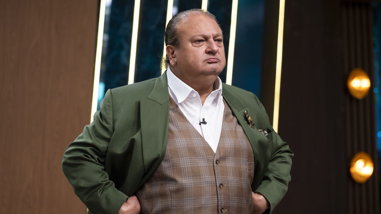 Erick Jacquin, de blazer verde com mãos na cintura, no estúdio do MasterChef Brasil