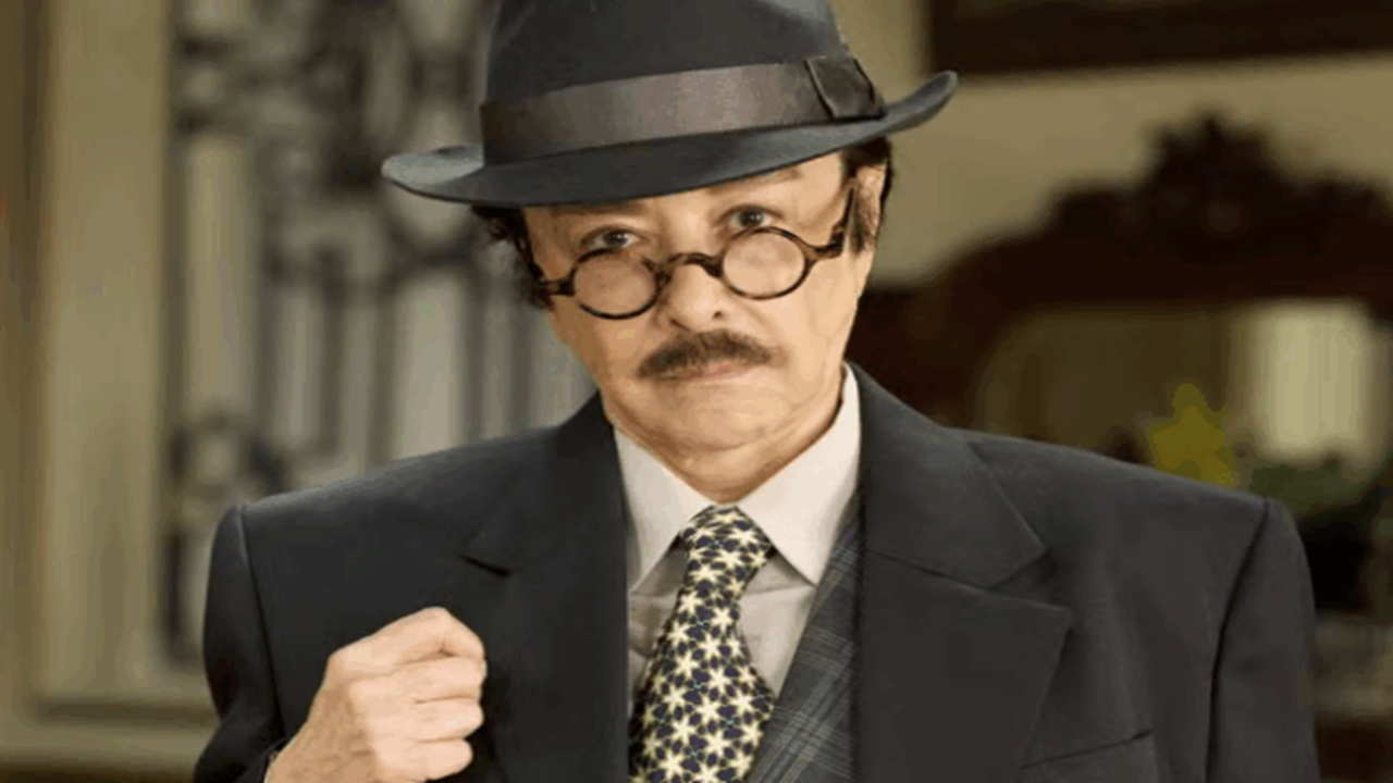 Nivea Maria caracterizada com chapéu e terno em cena da novela Êta Mundo Melhor!