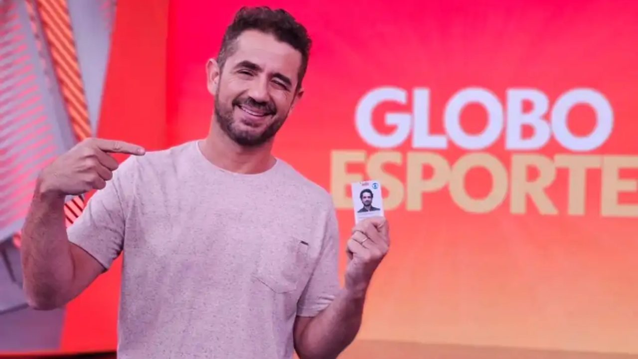 Foto de Felipe Andreoli segurando crachá da Globo no estúdio do Globo Esporte