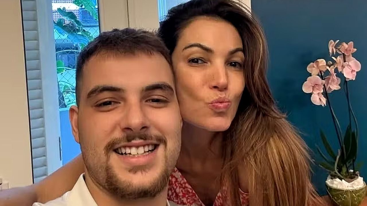 Homem e mulher sorrindo fazem selfie juntos em casa com vaso de orquídea ao fundo