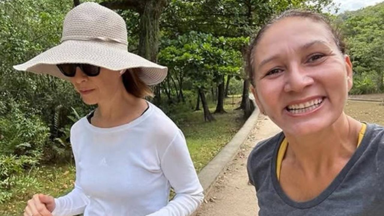 Foto de Fernanda Torres com chapéu e óculos escuros com mulher sorrindo para a câmera