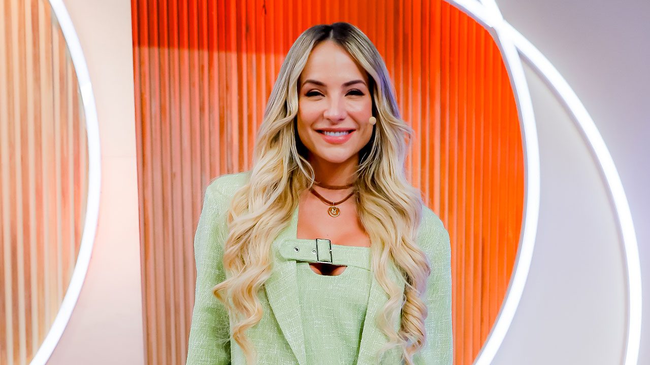 Gabi Martins sorrindo no palco do Sabadou com Virgínia do SBT usando blazer verde claro