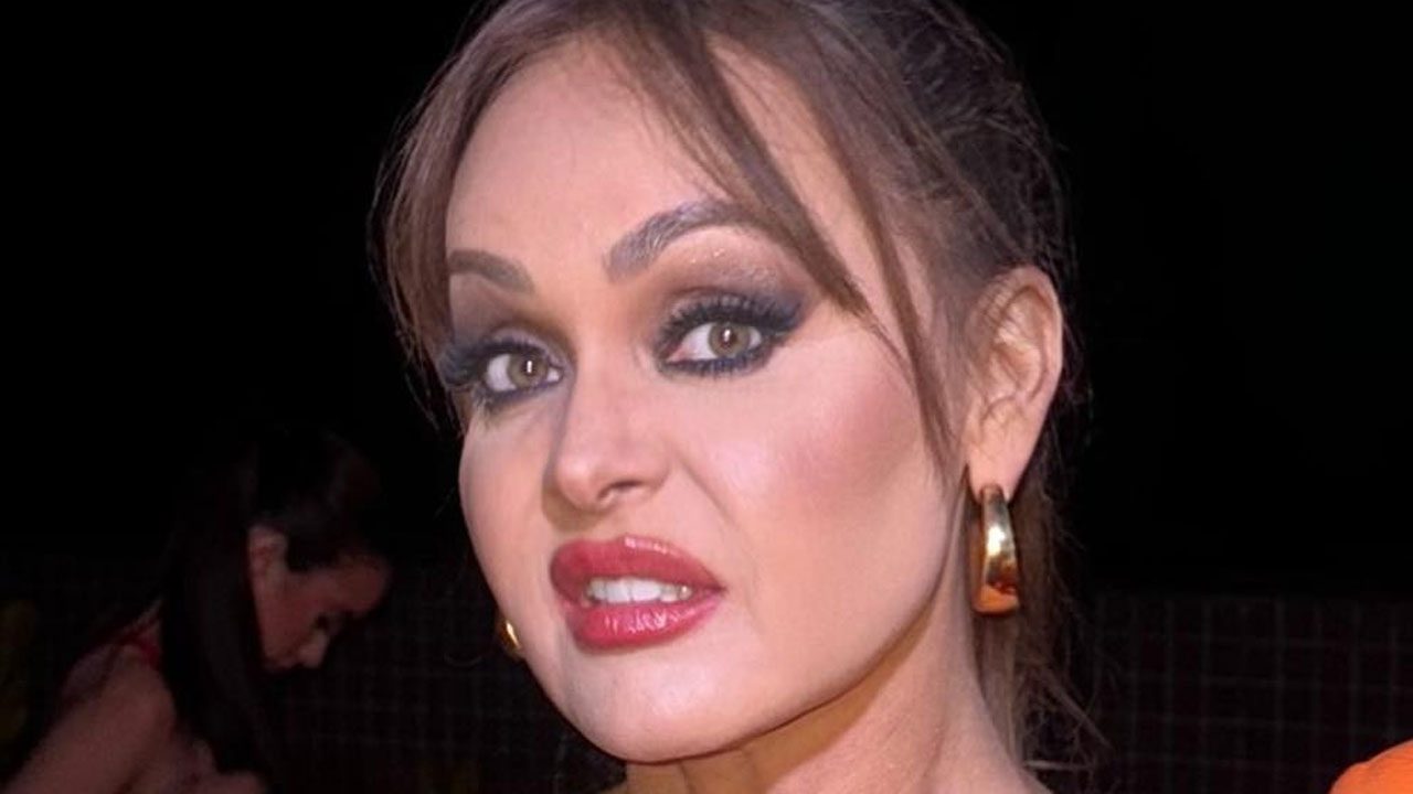 Gabriela Spanic com maquiagem marcada e batom vermelho usando brincos dourados em evento noturno