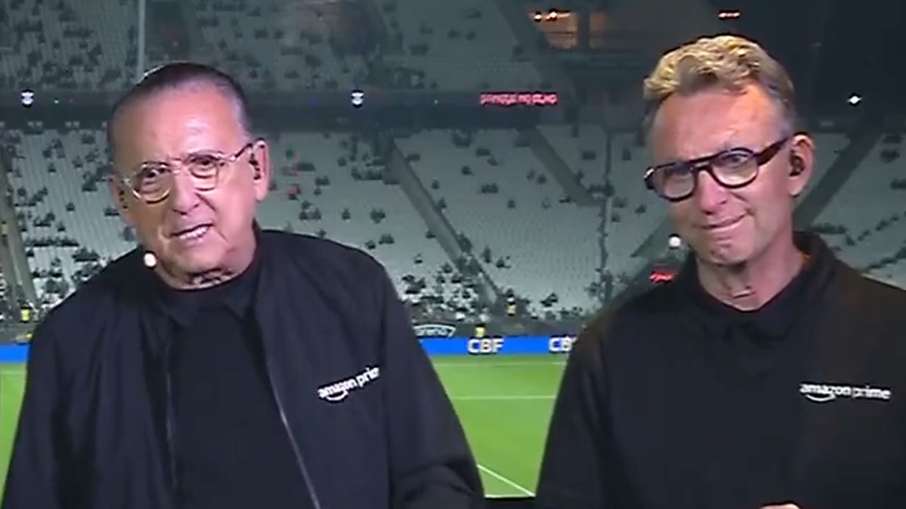 Galvão Bueno e Craque Neto com microfones e roupas do Prime Video em cabine de transmissão durante jogo da Copa do Brasil