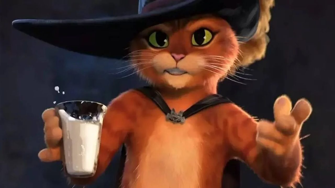 Personagem animado de gato alaranjado com olhos verdes usa chapéu preto de aba larga e capa escura presa por um broche, segurando um copo de leite com uma das patas enquanto olha para a frente com expressão confiante em um ambiente escuro.