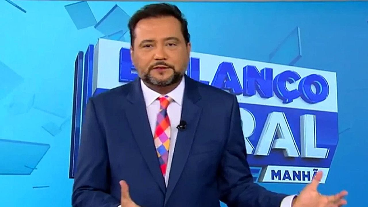Geraldo Luis apresenta o Balanço Geral Manhã em estúdio usando terno azul e gravata colorida