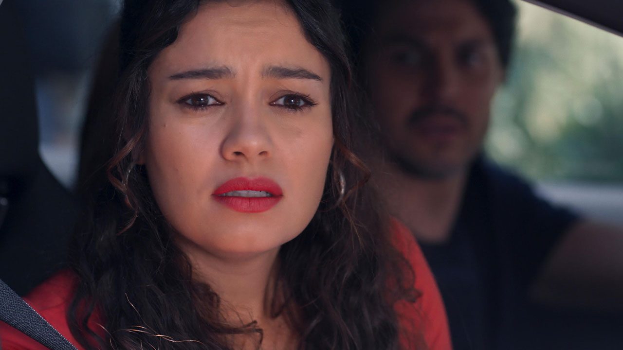 Sophie Charlotte como Gerluce chora com batom vermelho enquanto Romulo Estrela como Paulinho a observa dirigindo em cena de Três Graças